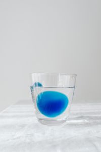 Kaboompics - Single Blue Accent in a Glass of Water on White Linen, Vertical Hydration Concept