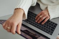 Kaboompics - Faceless Woman in White Sweater Working on Laptop with Gold Rings