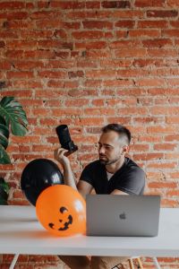 Kaboompics - Photographer with Camera, MacBook and Halloween Balloons at Desk