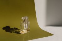 Kaboompics - Clear Perfume Bottle on an Olive Green Backdrop