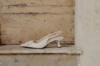 Kaboompics - White high-heeled open-back pumps with front embellishment - Pointed toe - Ankle strap