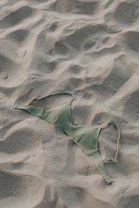 Kaboompics - Green Bikini Top on Rippled Beach Sand, Minimal Swimwear Flat Lay