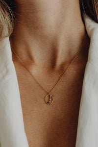 Kaboompics - Delicate Gold Pendant Necklace over a White Blazer, Minimal Jewelry Styling