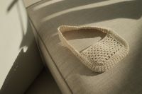 Kaboompics - Close-Up Beige Crochet Tote Bag on a Neutral Upholstered Seat in Direct Sunlight