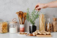 Kaboompics - Hand Holding Fresh Rosemary over Glass Jars of Pasta, Flour and Chickpeas