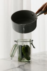 Kaboompics - Pouring Water into a Cucumber Jar with White Background and Copy Space