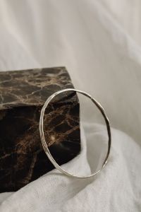 Kaboompics - Large Silver Hoop Bangle against Dark Marble and White Linen