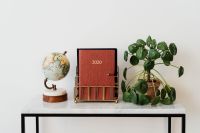 Kaboompics - Red 2020 Planner with Globe and Pilea on White Marble