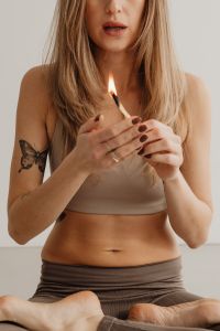 Kaboompics - Seated Woman Lighting a Palo Santo Stick With Both Hands