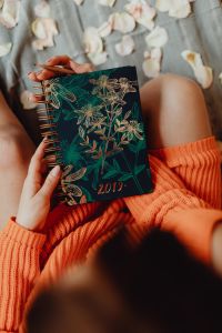 A woman in an orange sweater holds the 2019 calendar in her hands