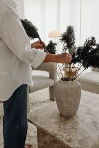 Kaboompics - Woman Arranging Dried Branches in a Vase by a Window