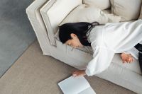 Kaboompics - Woman Reading a Book While Lying on a Linen Sofa