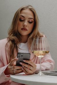 Kaboompics - Woman Using a Smartphone Beside a Wine Glass