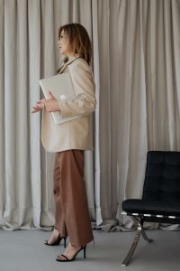 Kaboompics - Businesswoman Holding a Closed Laptop beside Neutral Curtains