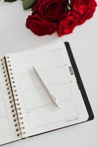 Kaboompics - Vertical Weekly Planner with Red Roses and Pencil on White Desk