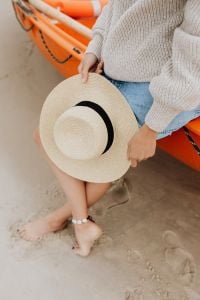 Kaboompics - Woman Sitting Barefoot in Shallow Seawater with a Straw Sun Hat and Orange Kayak