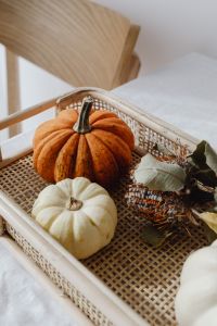Kaboompics - Orange and White Pumpkins with Dried Leaves in a Wicker Tray on White Linen