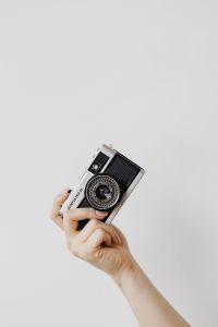 Kaboompics - One Hand Holding an Olympus Trip 35 Against a Minimal White Background