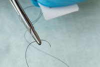 Kaboompics - Surgical Suture Needle Against Blue Clinical Background