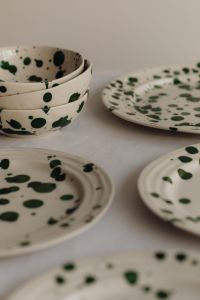 Kaboompics - Stacked Green Splatter Bowls and Plates on Neutral Linen