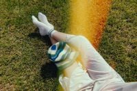 Kaboompics - Overhead Woman in White Outfit Resting on Sunlit Grass with Film Grain