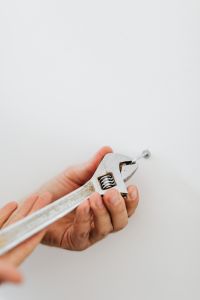 Kaboompics - Hands Using an Adjustable Wrench to Tighten a Wall Fastener, DIY Home Repair
