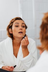 Kaboompics - Vertical Bathroom Mirror Portrait of a Woman Applying Lip Gloss with a Wand