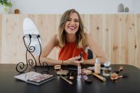 Kaboompics - Smiling Woman at a Makeup Vanity with Lipstick, Eyeshadow Palette and Brushes