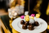 Kaboompics - Decorative Chocolate Pralines on White Plate with Festive Golden Bokeh