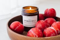Kaboompics - Close-Up of a Lit Soy Candle and Red Plums for Cozy Lifestyle Campaigns