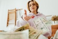 Kaboompics - Woman Reaching Toward Dollar Bills at Home