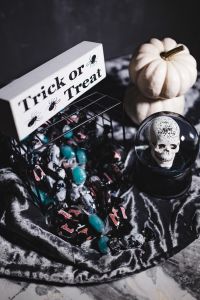 Kaboompics - Halloween Decor Basket with Candy, Skull Globe, White Pumpkins and Treat Sign