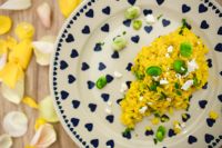 Kaboompics - Yellow rice with greens on a cute plate with blue hearts and a table decorated with flower petals