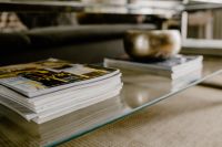 Kaboompics - Home Decor Magazines and Brass Bowl on Glass Coffee Table beside Dark Sofa