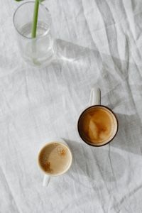 Kaboompics - Coffee Cups and Green Stem on a White Linen Table