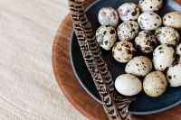 Kaboompics - Navy Plate of Speckled Eggs and Feather with Linen Copy Space, Spring Food Background
