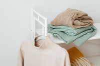 Kaboompics - Folded Sweaters With a Beige Garment on a White Rack