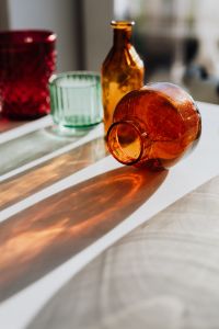 Kaboompics - Amber Bottle Beside Green Glassware with Long Shadows