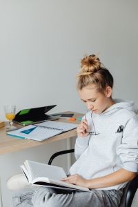 Kaboompics - Teenage Girl Reading Book beside Laptop and Study Notes