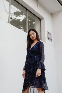 Kaboompics - Cropped Asian Woman in Navy Polka Dot Dress against White Architectural Background