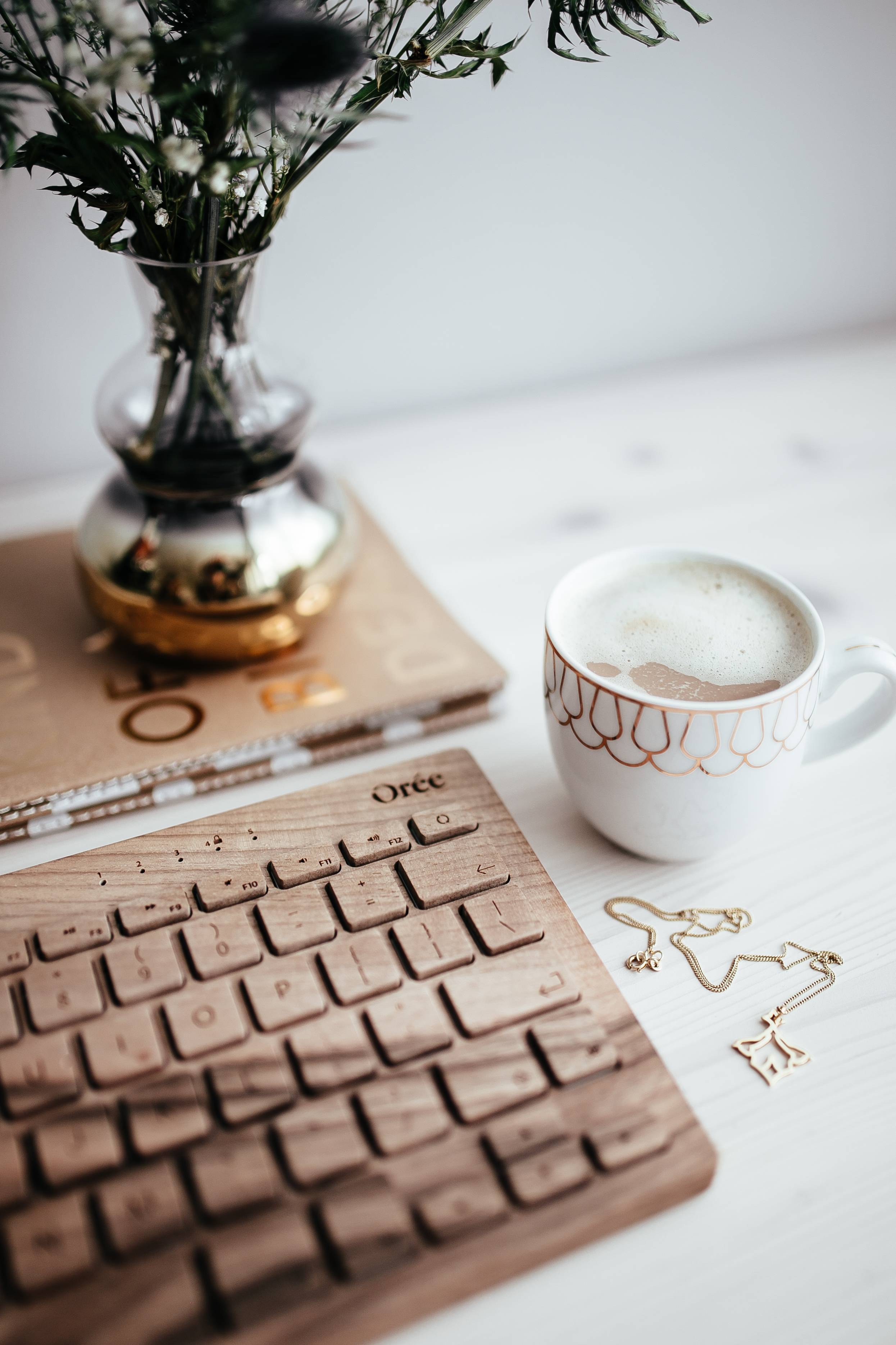 Wooden keyboard, cup of coffee, pineapple and golden jewellery