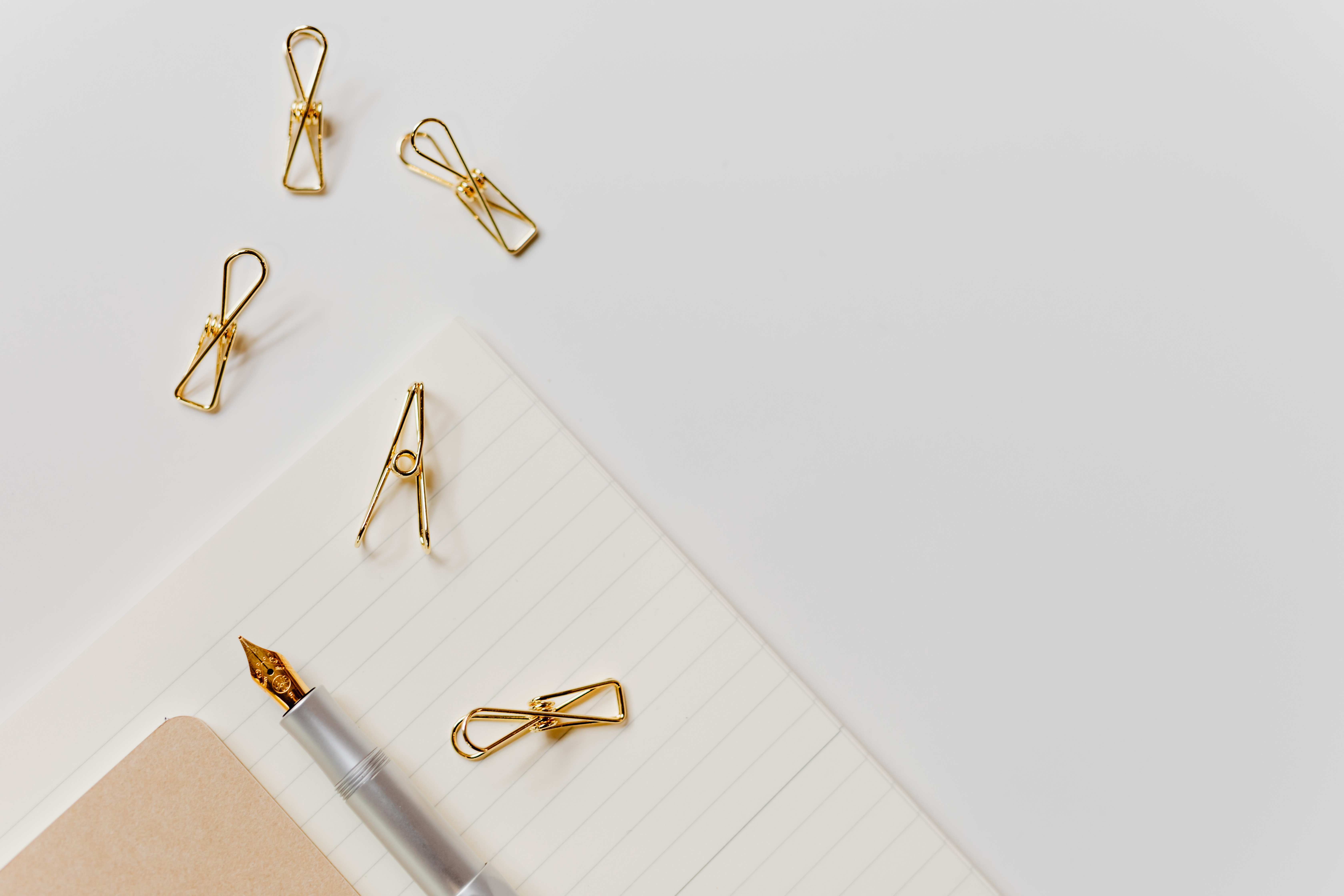 Fountain pen, clips and notebooks on a white desk