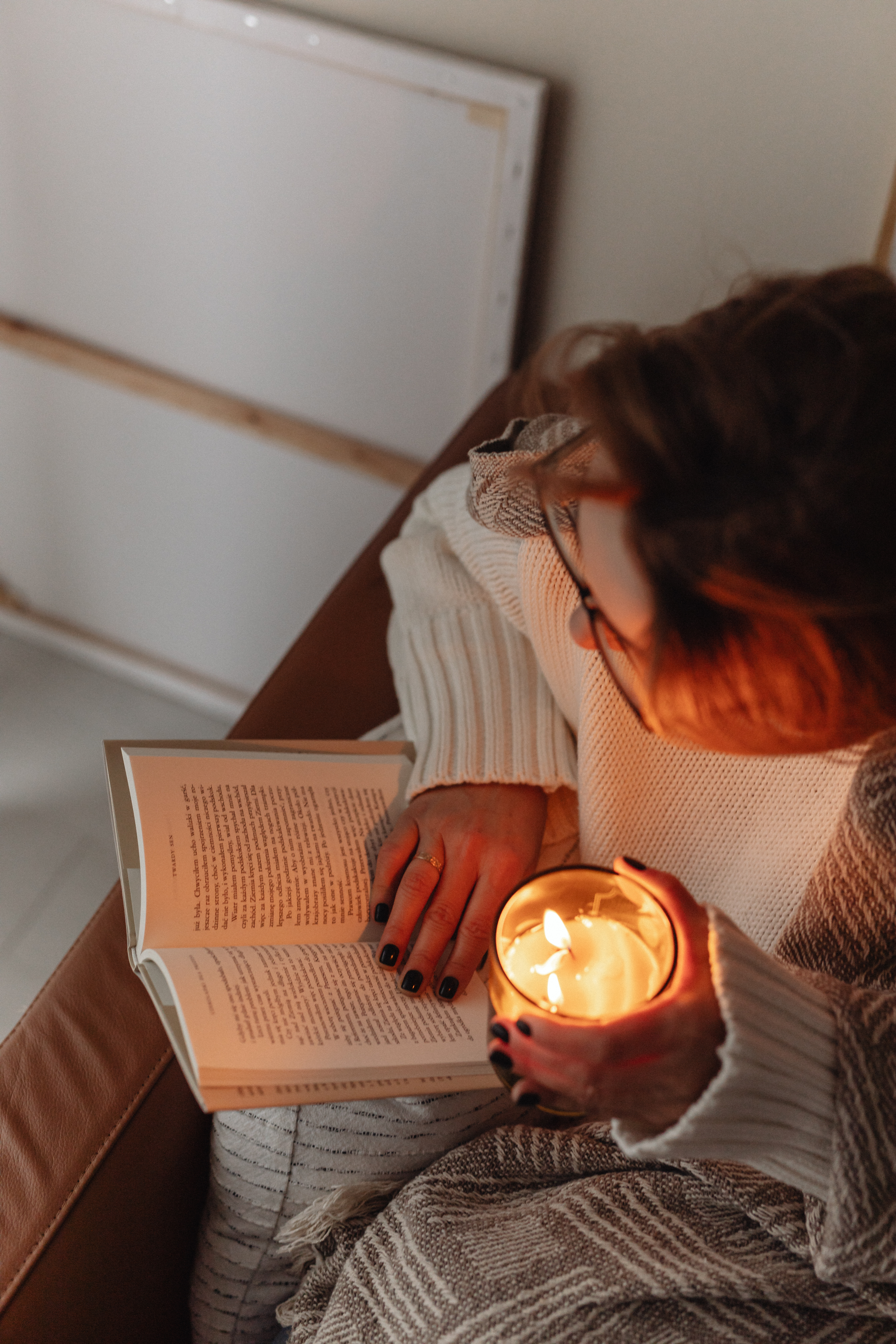 A woman holds a burning candle in her hands - reading a book
