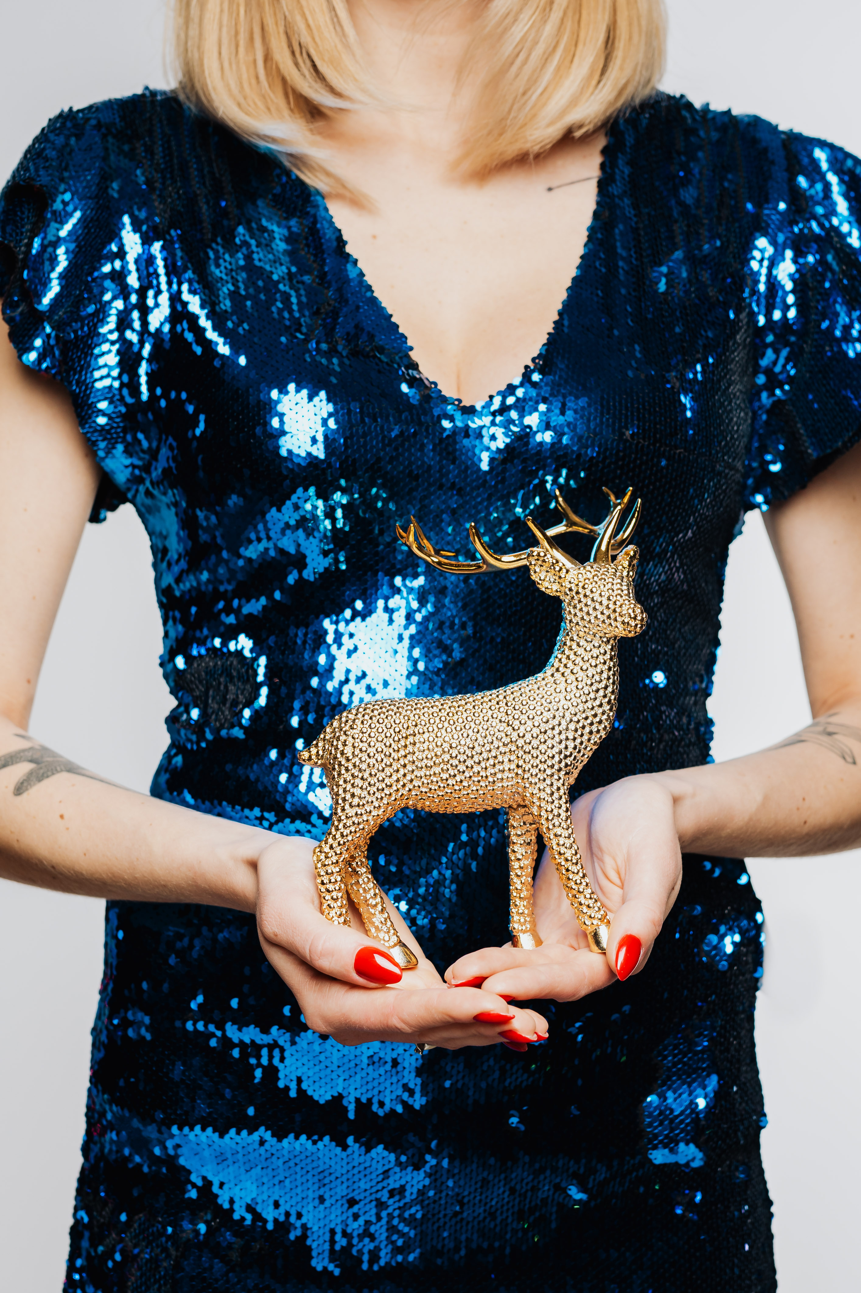 Woman in Blue Dress Holds Gold Reindeer