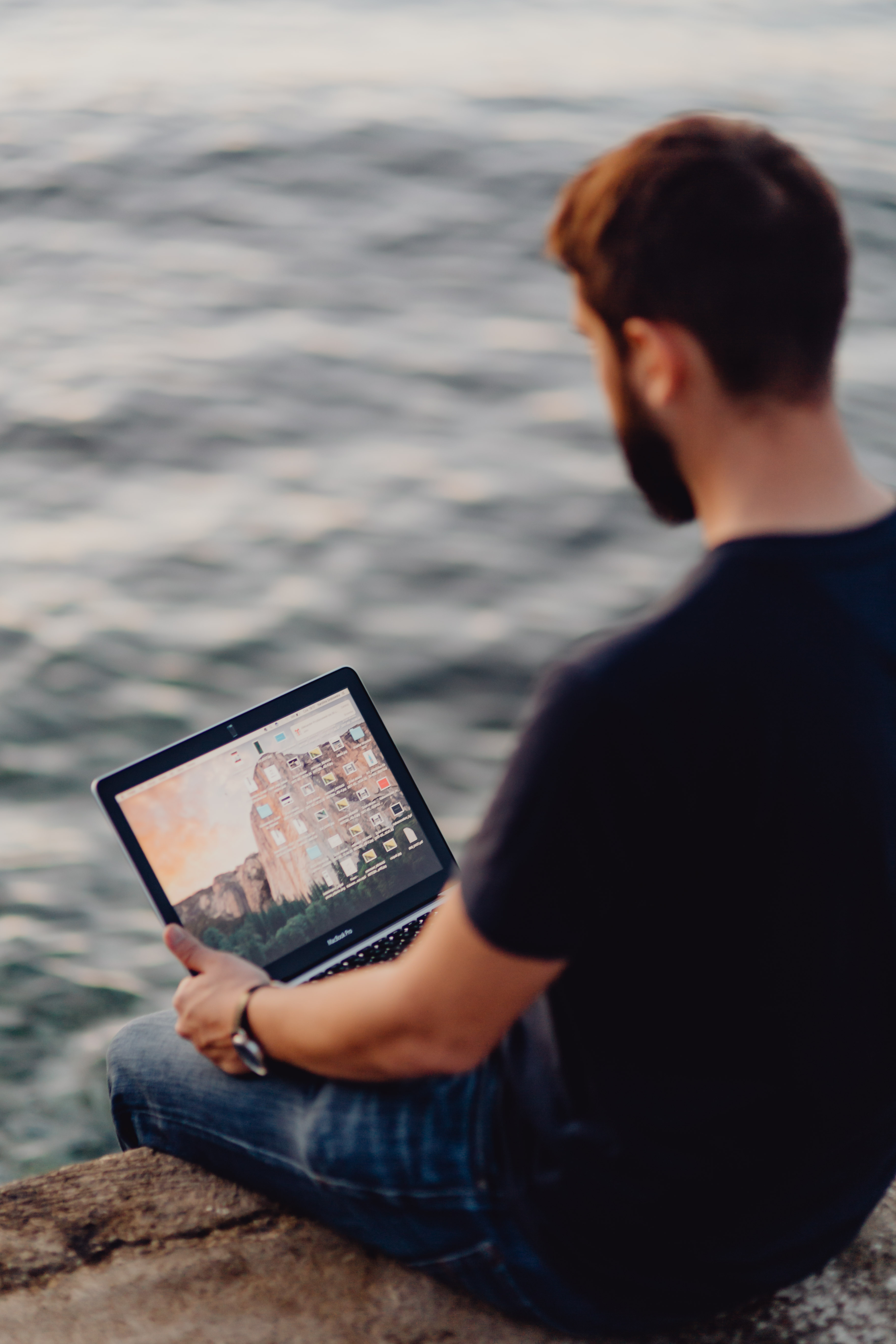 A man using a Macbook laptop at the seaside