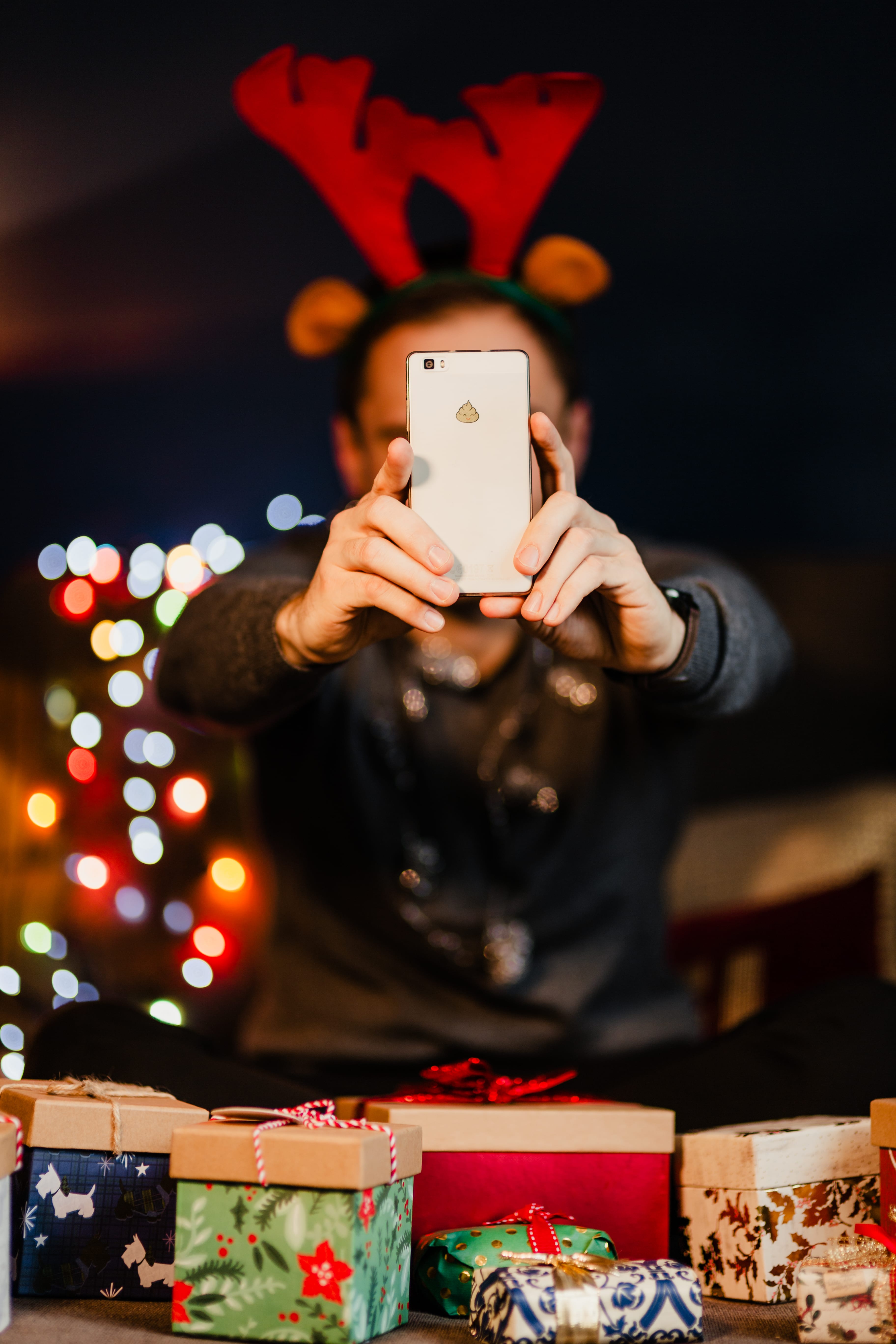 A handsome man with Christmas presents takes pictures with his phone