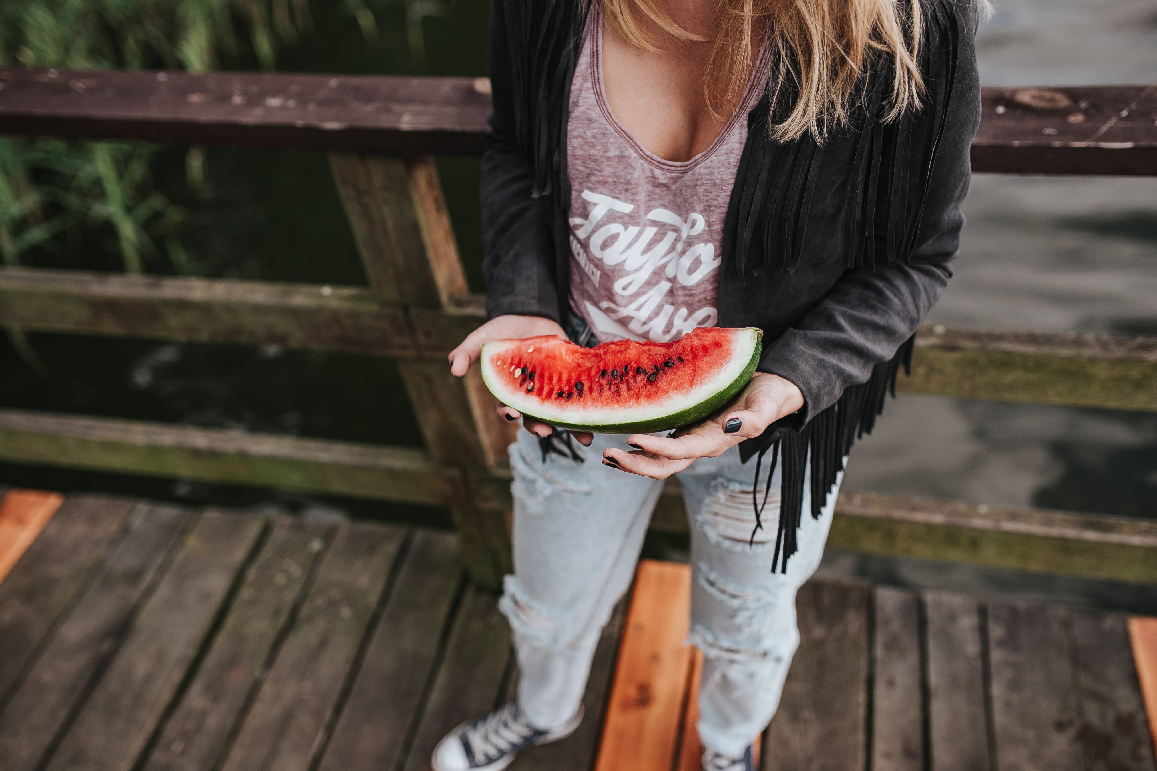 Blonde woman having a healthy snack at the wooden pier