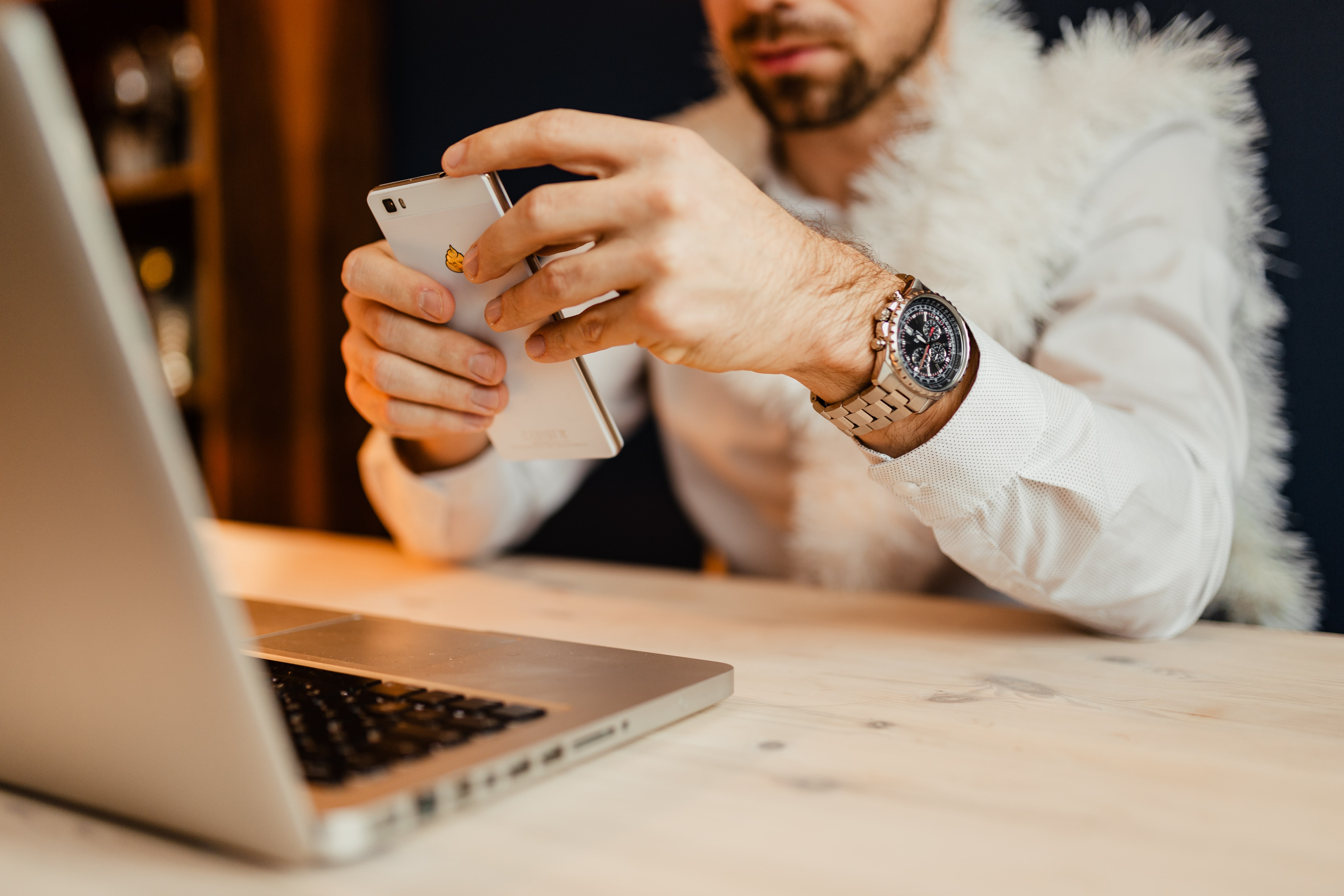 The designer sits at his desk and using his phone & laptop