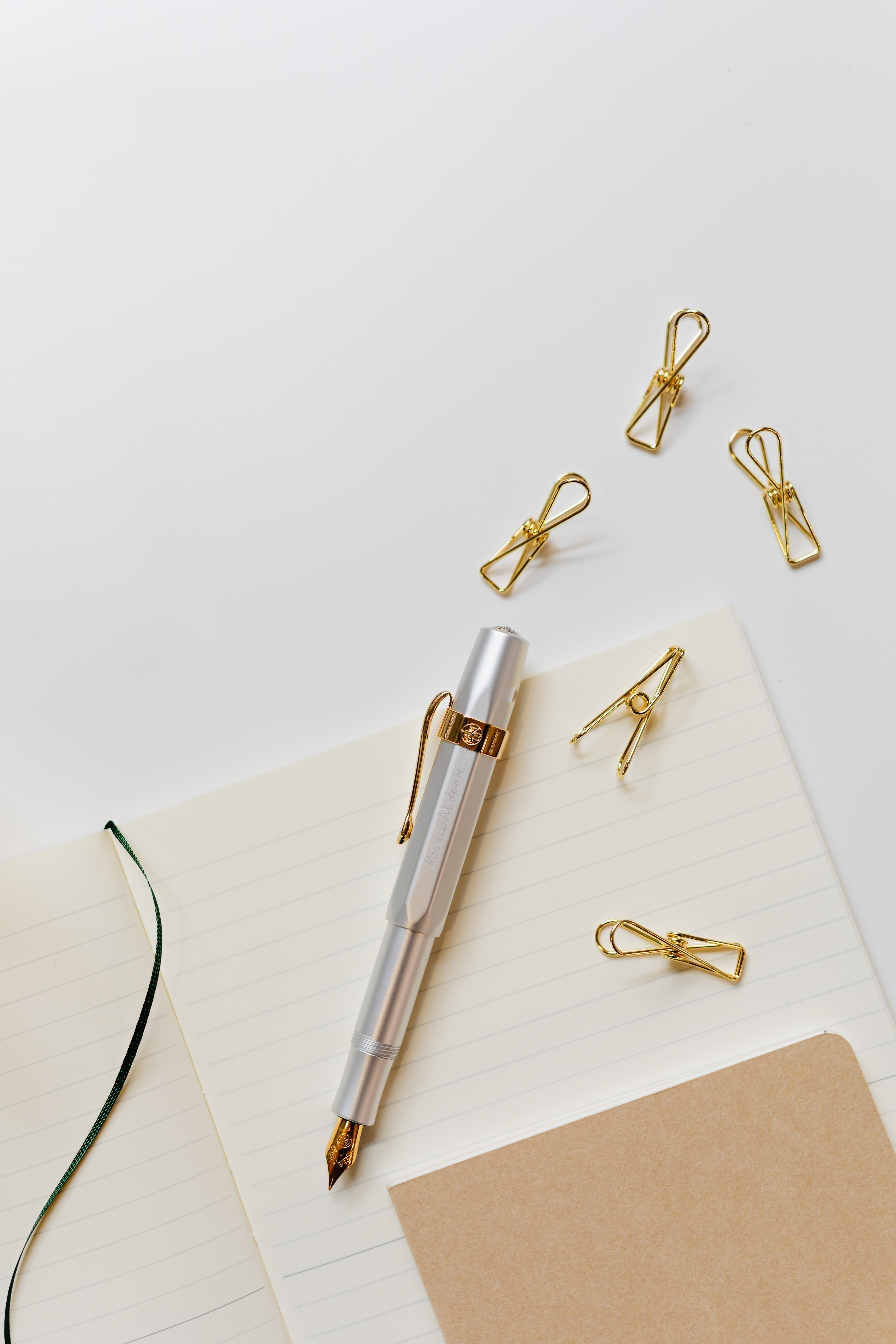 Fountain pen, clips and notebooks on a white desk