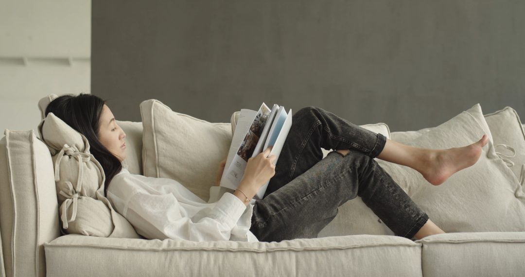 Woman Lying on The Couch Reading a Book